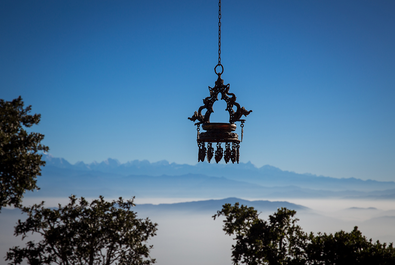 Traditional hanging lamp at Chandragiri Hills with a serene Himalayan mountain backdrop